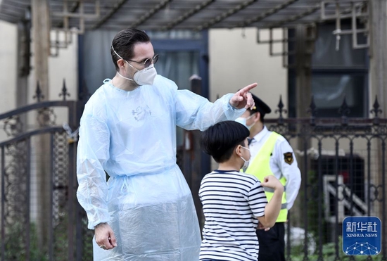 5月22日，在天津市南开区时代奥城社区核酸检测点，李翰文在帮一名小朋友指路。新华社记者 赵子硕 摄