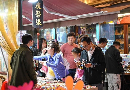 ↑4月29日晩,游客在天津古文化街一店铺选购商品。
