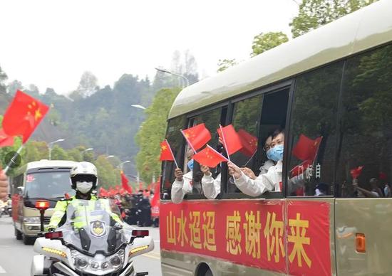 天津医疗队队员向群众挥旗示意