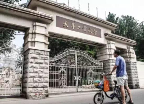 年过七旬的退休老教师站在校门前。