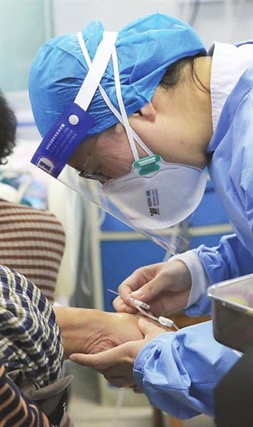 医科大学第二医院急诊科护士吴龙雪前一天晚上还在高烧，转天依然坚守岗位，图为吴龙雪正在给病人进行留置针穿刺。
