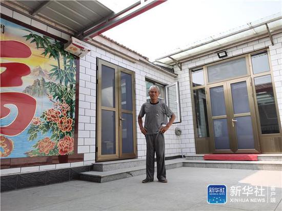 天津市静海区大丰堆镇高小王庄村村民陈克勤站在新房前(7月7日手机拍摄)。新华社记者 刘惟真 摄