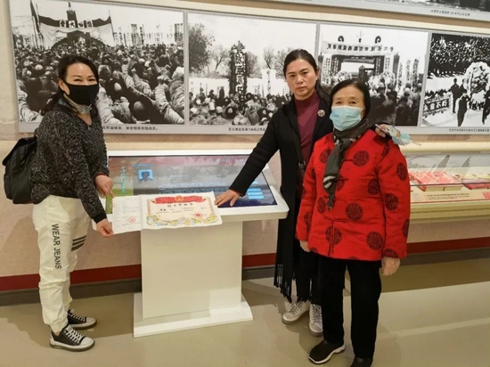 ▲陆芹（左一）和姐姐陆平、母亲张登玉，在平津战役纪念馆张豪的电子档案前合影