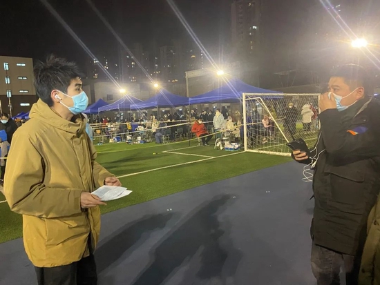 2022年1月9日,天津市南开区中营小学核酸采样点,中央广播电视总台天津总站记者孙强(左)在现场直播前与导播毕博超(右)进行沟通。他们团队为观众实时直播天津核酸检测情况,并梳理疫情出现后的48小时内当地采取的防控举措。