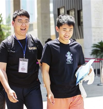 王鑫（左）迎接走出考场的学生。 记者 刘欣 摄