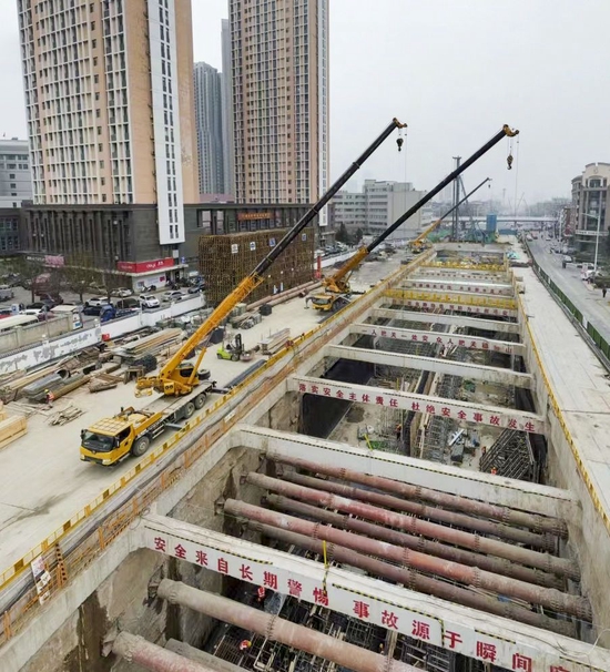 ↑在天津地铁8号线一期工程5标项目湘江道站至土城站区间明挖停车线现场，大型机械在吊运施工装备（2月11日摄，无人机照片）。