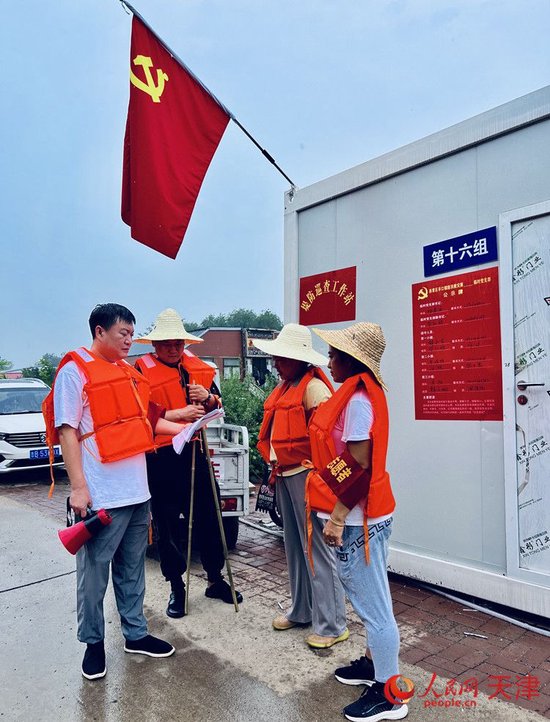 8月5日11:25,雨渐渐变小,毕红鸽向同组工作人员交代注意事项。人民网记者 孙翼飞摄