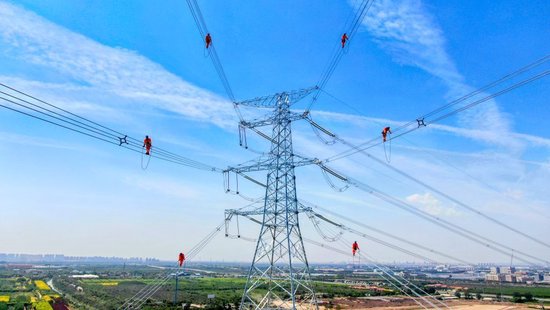 国网天津电力工作人员在板滨500千伏线路工程现场开展高空走线作业。6月6日摄 国网天津电力供图
