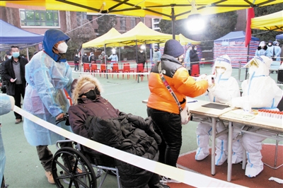 昨日，一名志愿者帮助行动不便的老人来到鞍山道小学进行核酸检测。