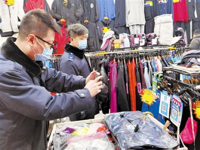 图为市场监管综合行政总队对淘宝城摊位、服装外贸销售单位进行执法检查。