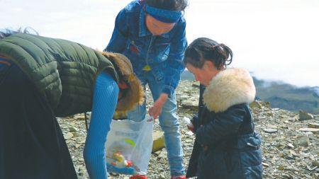 上居木村村民青梅和两个孙女在雪山上捡垃圾。