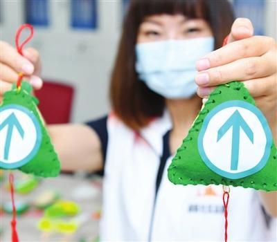 东丽区丽昕社区志愿者在制作完成的荷包上粘贴“绿码”。 本报记者 孙立伟 通讯员 杨同文 摄