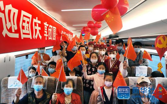 10月1日，乘坐京津城际C2020次列车的旅客与乘务人员在车厢内合影留念。（杨宝森  摄）