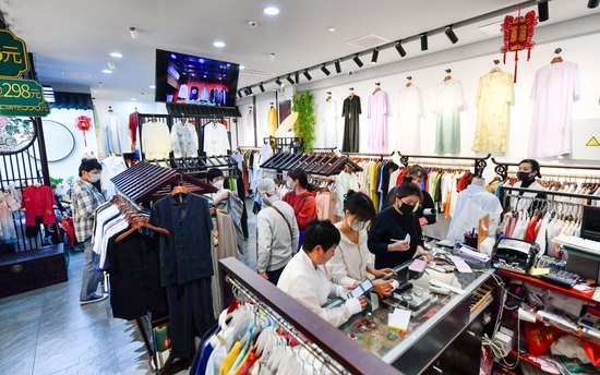 ↑4月29日，游客在天津古文化街一家服装店购物。