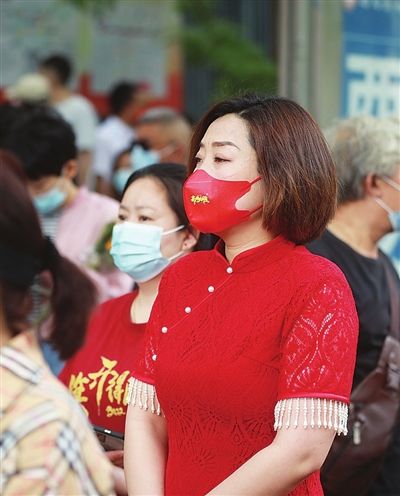 6月7日，崇化中学考点，一位考生家长穿着红色旗袍带着“高考必胜”字样的红口罩，寓意“旗开得胜”。
