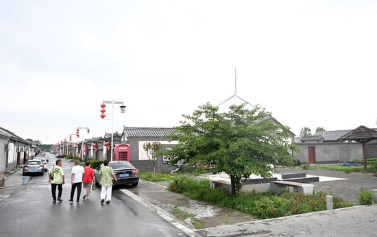 游客在天津市宝坻区黄庄镇小辛码头村街巷内游玩(6月29日摄)。