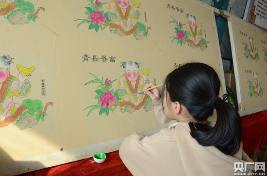 董静的孙女在为年画上色