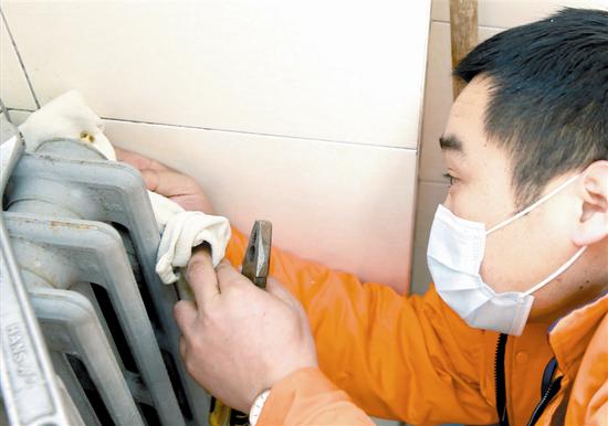 維修工作人員在衞生間內更換老舊的暖氣閥門