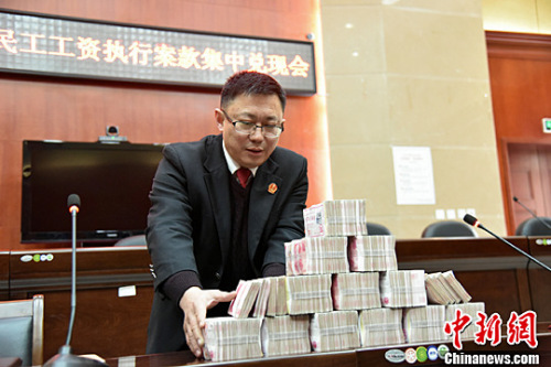 2016年1月份,北川法院为农民工讨薪,145万工资集中兑付,执法人员正在清点成捆的钞票。