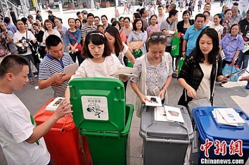 图为市民参与“丢垃圾”游戏,培养垃圾分类意识。