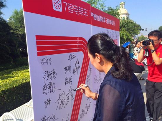 图片:南开区文明办主任路彤在7号电单车文明骑行宣传展台上签字