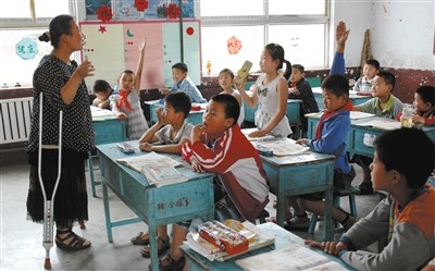 山东省枣庄市陶庄镇种庄中心小学教师孟凡芹在和孩子们做游戏。左腿被截肢的孟凡芹,单腿站立、跳跃上课已19年。图/视觉中国