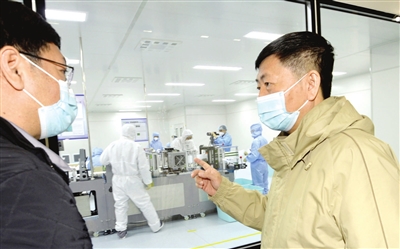 张秉军（右）在泰达洁净公司防疫材料生产一线指导N95口罩生产。本报记者 王涛 摄