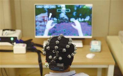 患者用自己的意念控制机电辅助装置带着手活动。