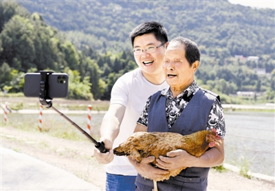 5月13日,李君(左)与村民拍摄短视频,向网友介绍岫云村养殖的“时光鸡”。