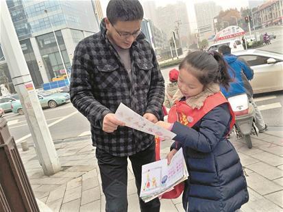 图为:武昌实验小学东湖国际校区学生向路人宣传文明过马路