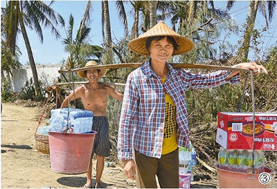图③:22日,海口市三江农场上山村村民挑着领到的救灾物资。