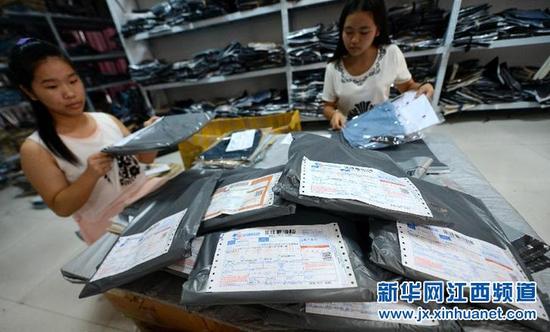 7月25日,在新余市高新区网店一条街,一家服装店工作人员在打包发货。