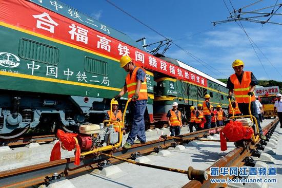 7月28日,建设者在合福高铁福建武夷山境内铺设最后一对钢轨
