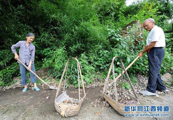 8月10日，吴传枝（右）和老伴郑雪钗在村口清理路面。