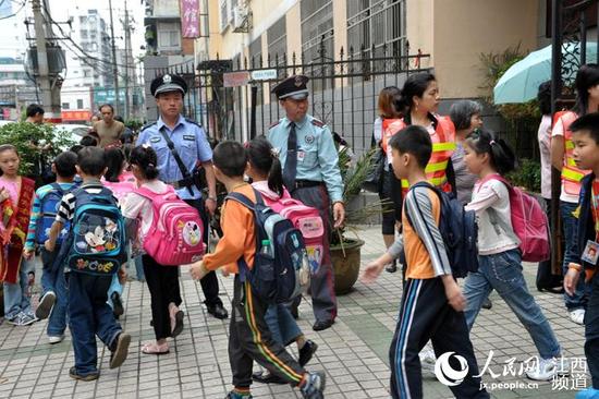 警察、辅警、安全员护送学生放学。江西3部门联合发文要求提高上放学时段校园周边的“见警率”。