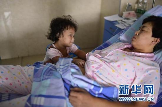 看到妈妈难受，只有三岁的小女儿婷婷模仿爸爸给妈妈按摩肚子（9月6日摄）。 新华社记者 周密 摄