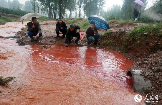 河南汝阳一河水遭污染呈血红色 工人用硫酸稀释