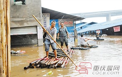 洪水淹没菜园坝竹木市场,市场经营户在公路上划船通行。