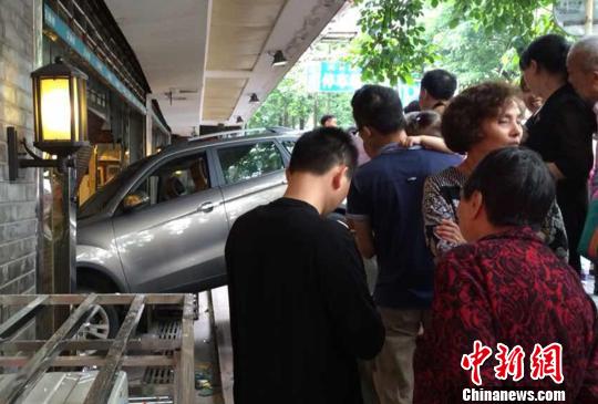 图为重庆大礼堂附近,一小轿车“开”进鸡汤馆吸引众多路人围观。