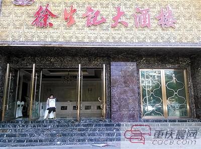 刘嘉抱着父亲遗像坐在事发酒店门口。
