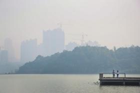 10月9日，长沙梅溪湖，一对情侣在湖边散步，对面的建筑若隐若现。