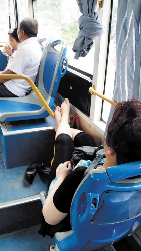 日前，在705路公交车上，一位女子为了舒服将一双赤脚搭在前方一横杆上，如此不雅动作不仅不文明，也影响其他乘客。贺文兵 摄