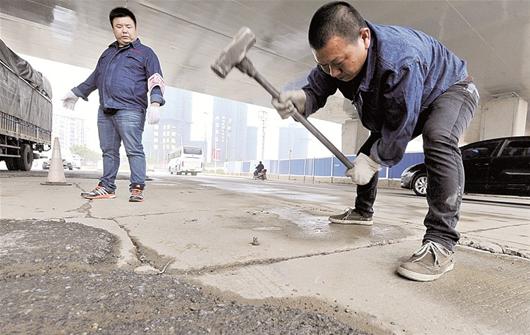 图为:谢舒明抡锤除钉,彭龙在一旁提醒车辆避让