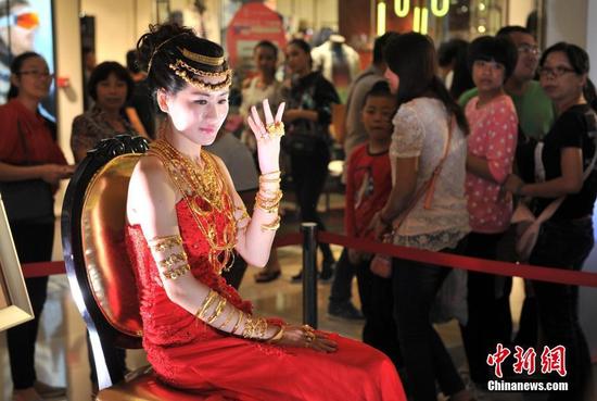 一浑身挂满黄金首饰的美女坐在福州商场内,吸引许多民众驻足观看。