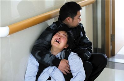 京京的母亲靠着丈夫在医院ICU外泣不成声。11月6日，2岁的京京落入热水桶，全身92%烫伤。