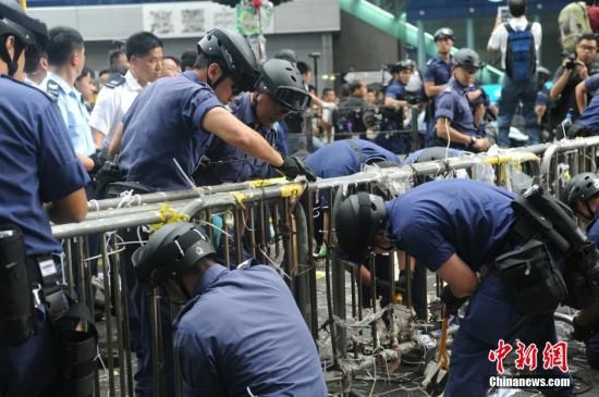 11月26日,香港法庭执达主任在旺角弥敦道执行禁制令,清除非法障碍物,后因受阻而要求警方协助执行。多名警员剪走路障上的索带。中新社发 谭达明 摄