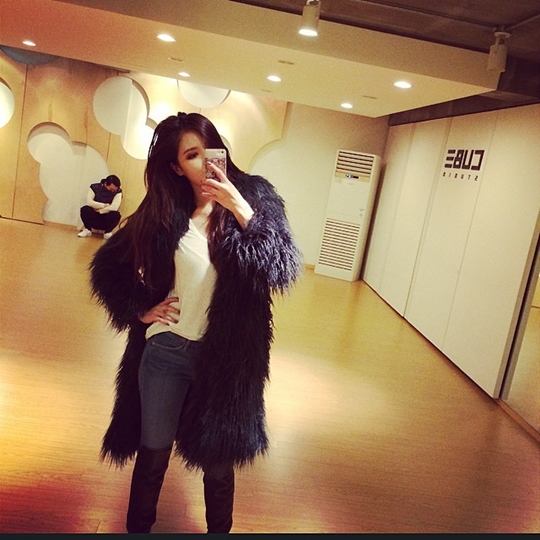 照片中,泫雅站在练舞室内,穿着白色t恤,牛仔裤,毛大衣,一手叉着腰