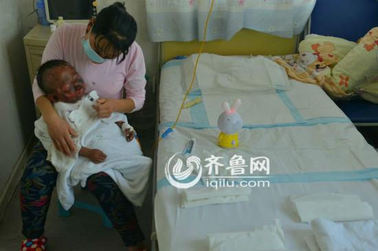 大部分时间里，甘梅英都保持着同一个姿势抱着儿子。（记者 于鹏 孔冠军\摄）