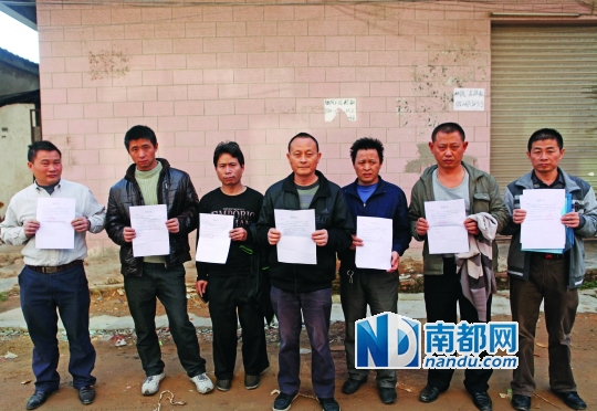 在东莞新力鞋厂附近的出租屋外,樊胜平(右一)等被厂方辞退的员工手里拿着解聘书一筹莫展。南都记者 刘媚 摄