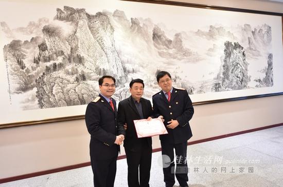 赠画后,画家徐家珏手持南宁铁路局签发的收藏证书,与南宁铁路局桂林车站站长汤继革(右)、党委书记钟万鸿(左)在画作前合影。首席摄影记者游拥军 摄